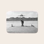 Steady as she goes girl in bikini on a dock with plane landing black and white photograph Bath Mat Gallery Image 1