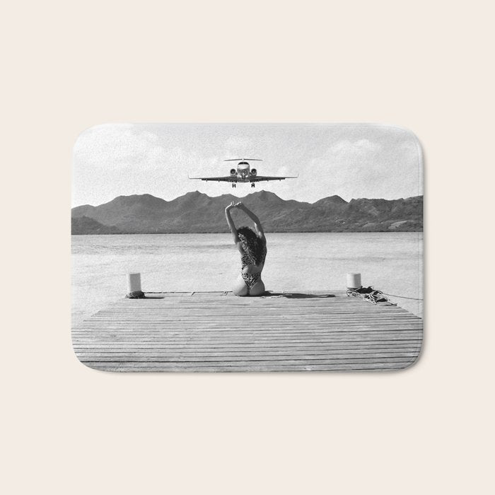Steady as she goes girl in bikini on a dock with plane landing black and white photograph Bath Mat Gallery Image 1