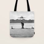 Steady as she goes girl in bikini on a dock with plane landing black and white photograph Tote Bag Gallery Image 1