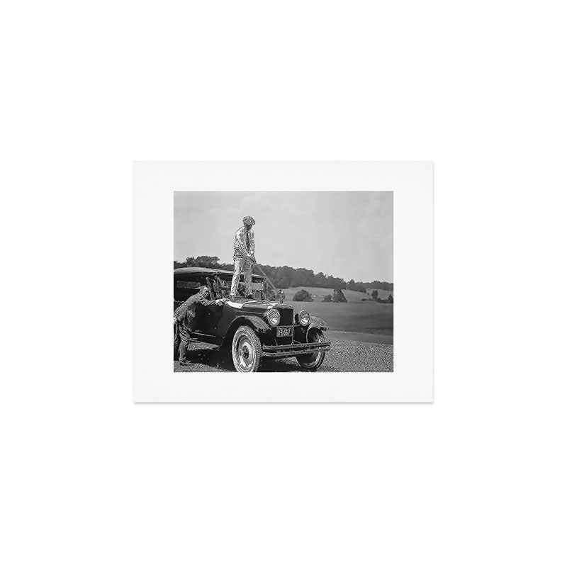 Pro golfer hitting golf ball off vintage car hood ornament on a dare par one 18th hole funny black and white golf sport photograph - photography - photographs Art Print Gallery Image 1