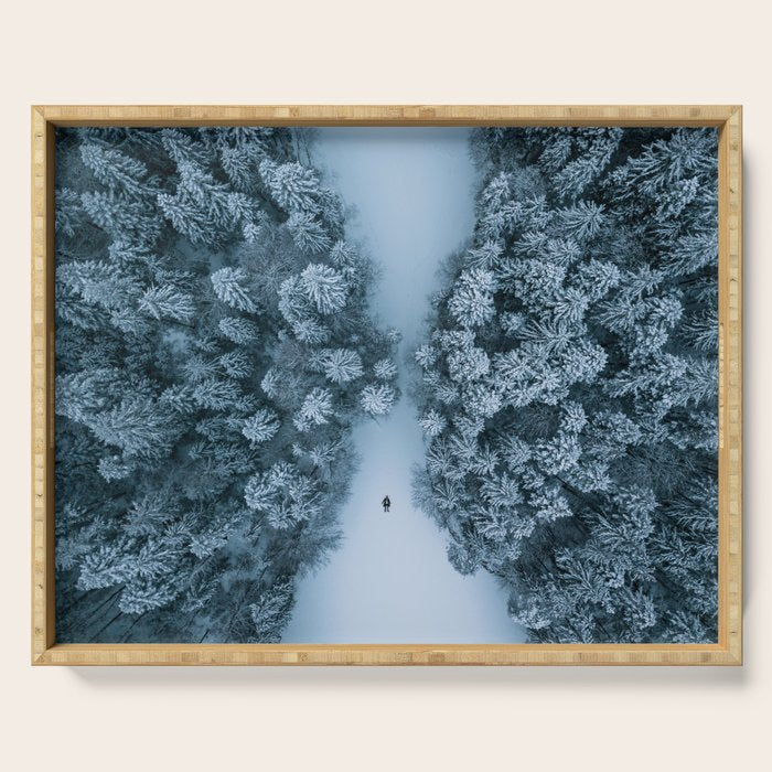 Man lying in the snow on a frozen lake in a winter forest - Landscape Photography Serving Tray Gallery Image 1