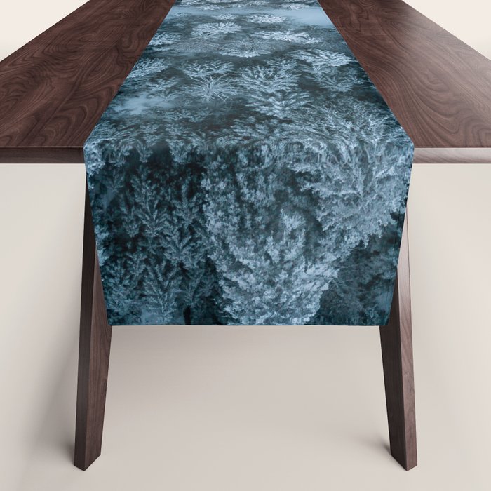 Man lying in the snow on a frozen lake in a winter forest - Landscape Photography Table Runner Gallery Image 1