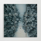 Man lying in the snow on a frozen lake in a winter forest - Landscape Photography Wood Wall Art Gallery Image 1