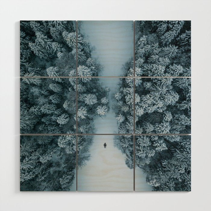 Man lying in the snow on a frozen lake in a winter forest - Landscape Photography Wood Wall Art Gallery Image 1