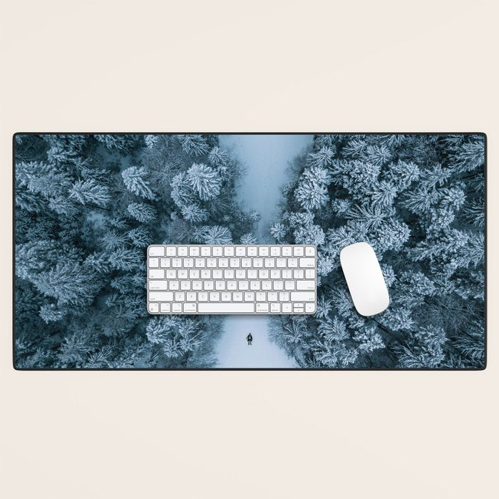 Man lying in the snow on a frozen lake in a winter forest - Landscape Photography Desk Mat Gallery Image 1
