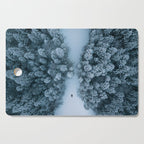 Man lying in the snow on a frozen lake in a winter forest - Landscape Photography Cutting Board Gallery Image 1