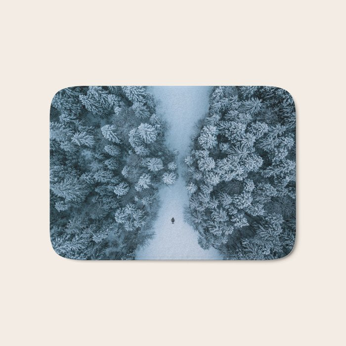 Man lying in the snow on a frozen lake in a winter forest - Landscape Photography Bath Mat Gallery Image 1