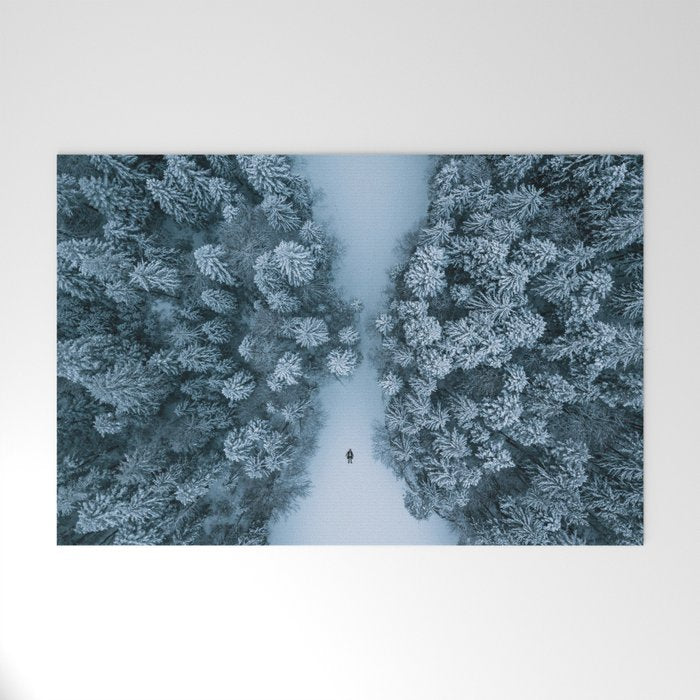 Man lying in the snow on a frozen lake in a winter forest - Landscape Photography Welcome Mat Gallery Image 1